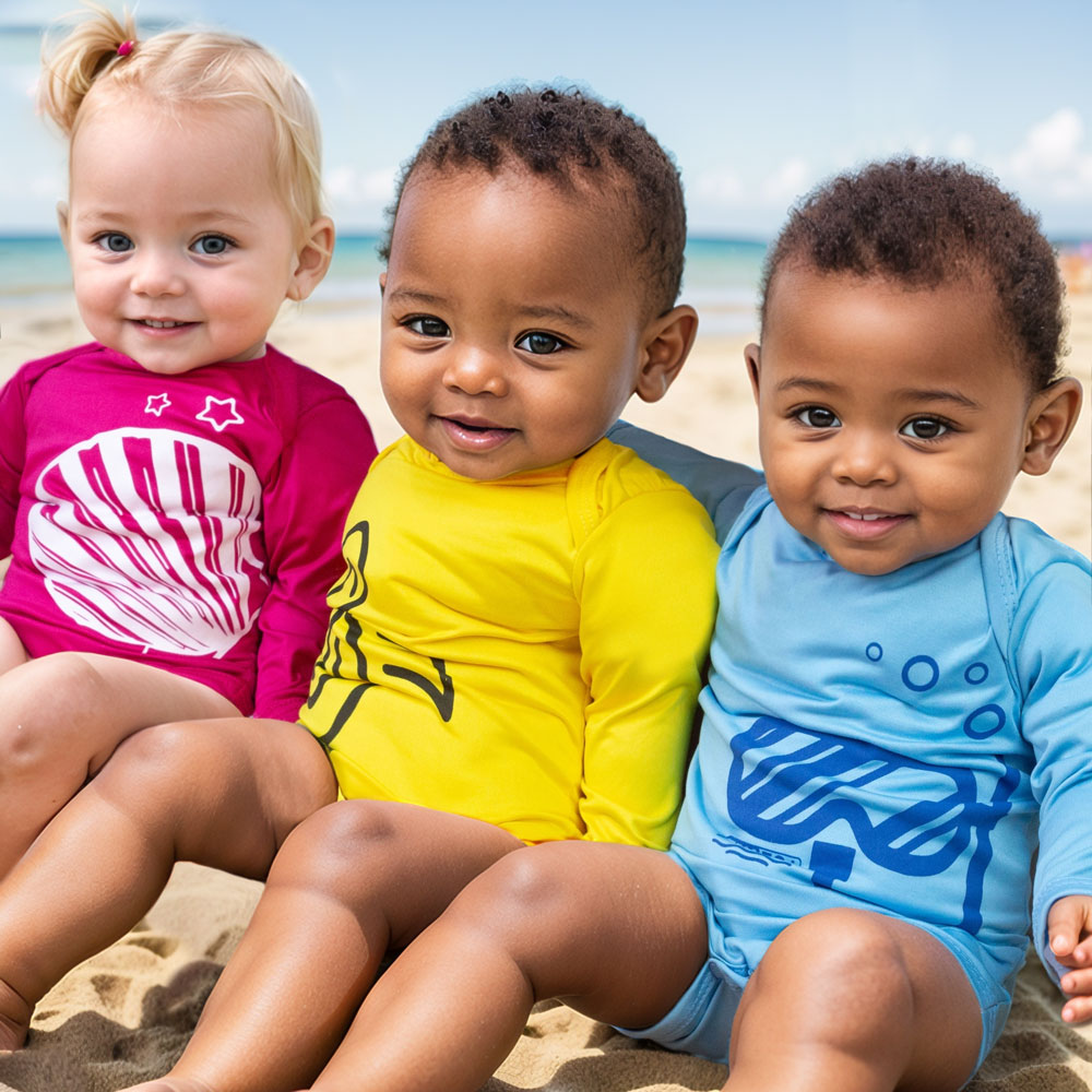 Beb&ecirc;s usando roupas com prote&ccedil;&atilde;o solar na praia