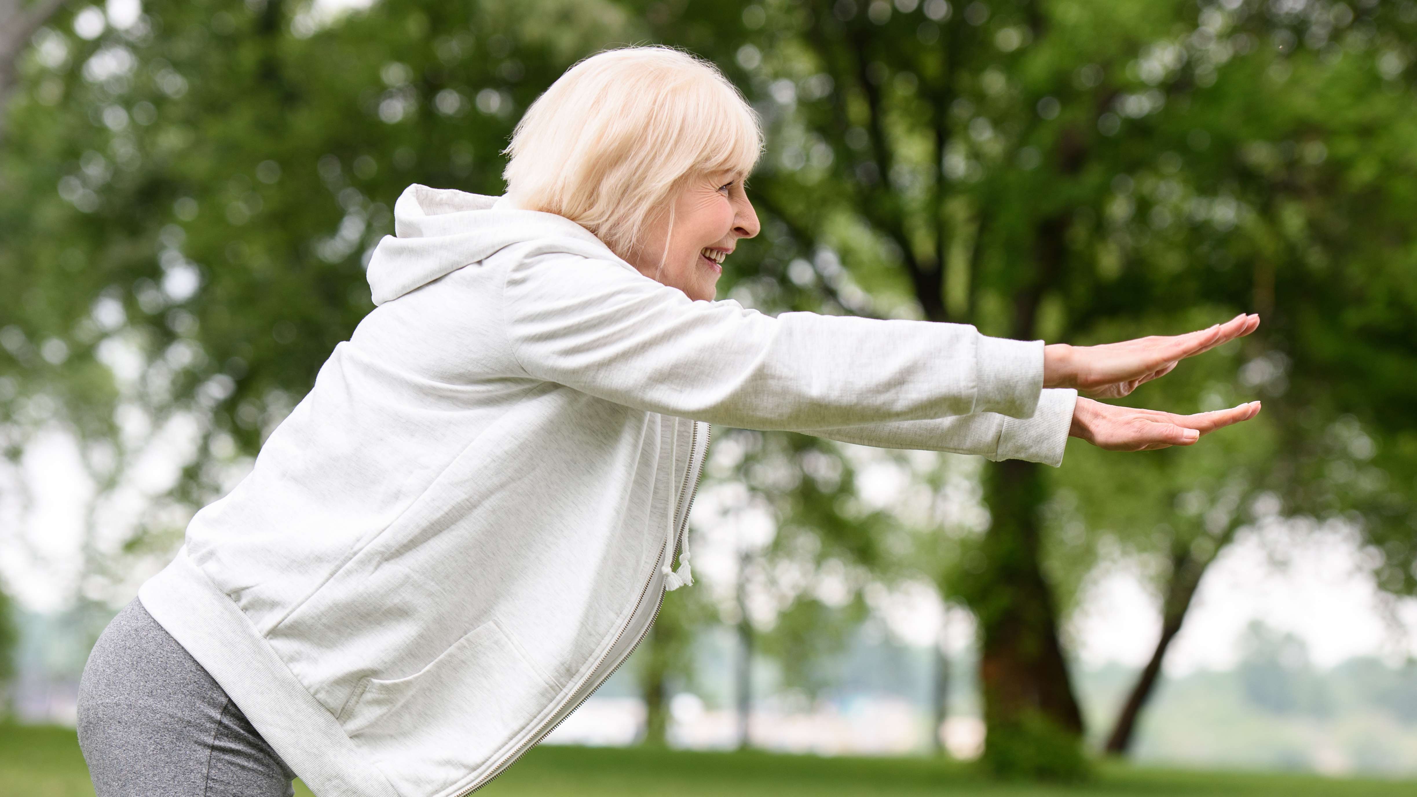 Patient stretching in park to help relieve symptoms of spinal stenosis