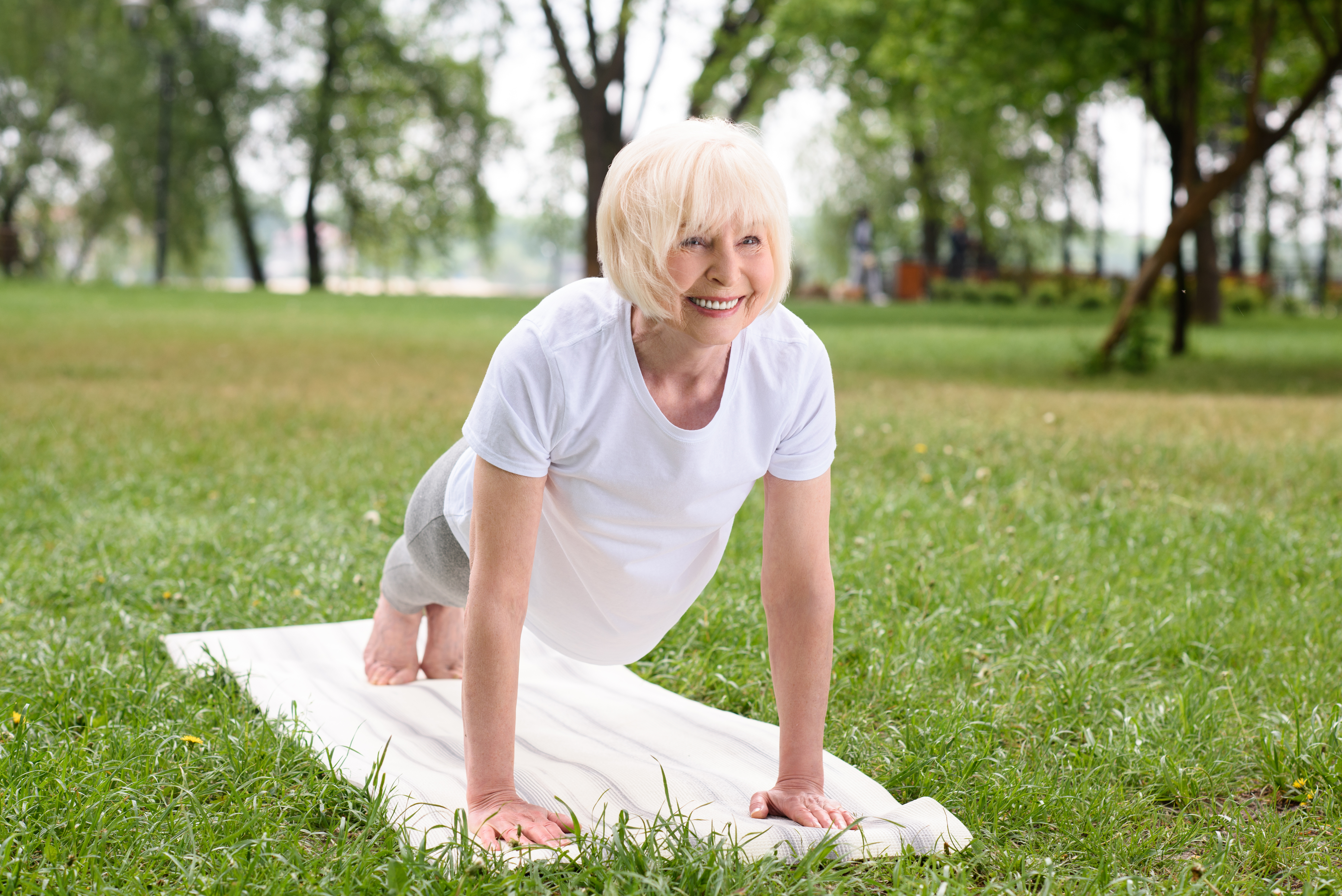 Woman doing strengthening exercises in park to reduce pain from spinal stenosis 