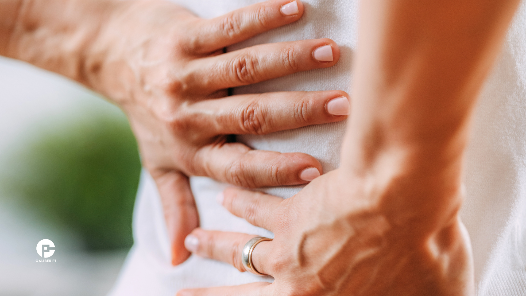 a person with back pain holding their hands to their back