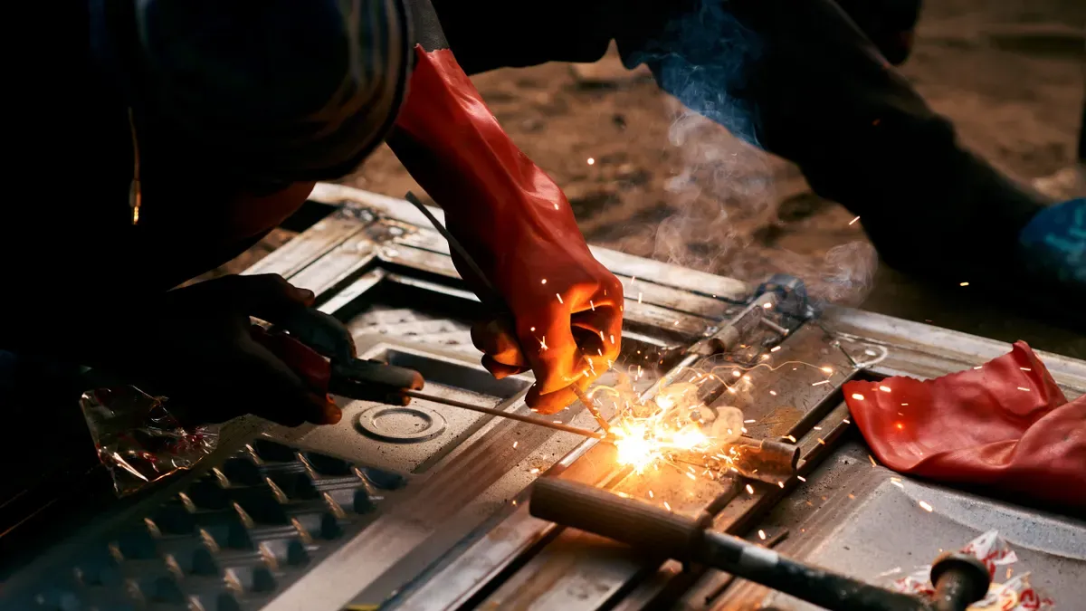 Welder in protective gloves cutting metal with a plasma torch