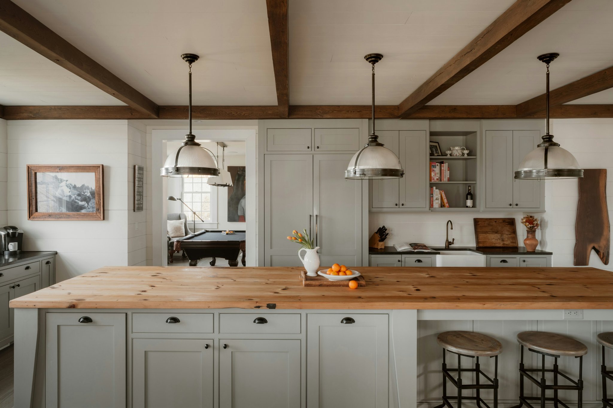 Large kitchen island with evenly spaced pendant lights creating balanced lighting design